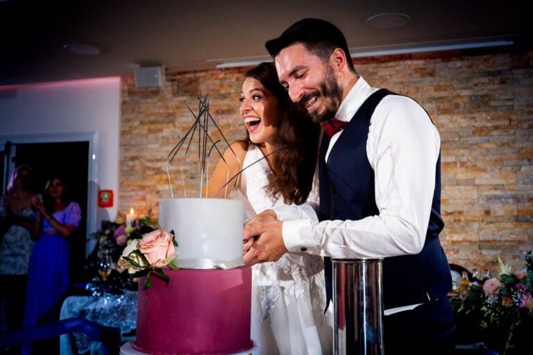 Das Brautpaar schneidet die Hochzeitstorte an bei ausgelassener Stimmung