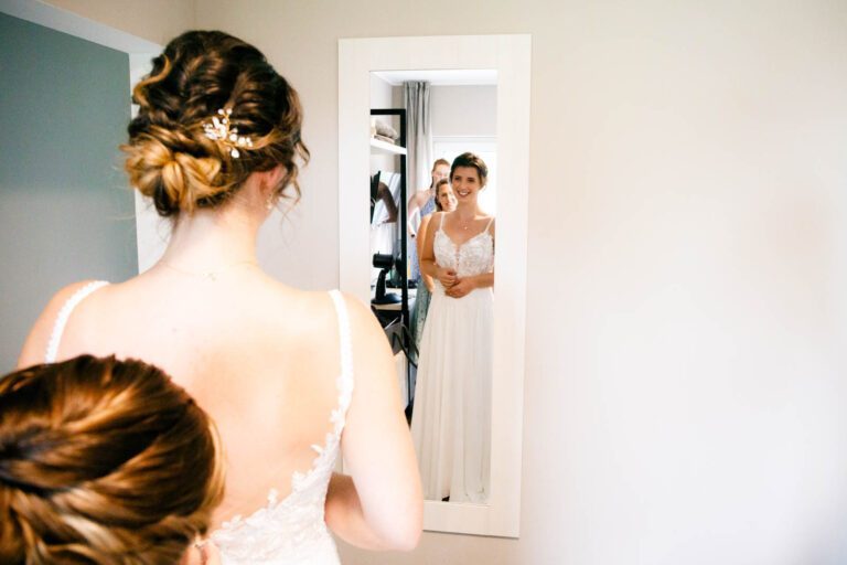 Elegantes Brautkleid im Hofgut Klostereck: Die Braut strahlt vor dem Spiegel.