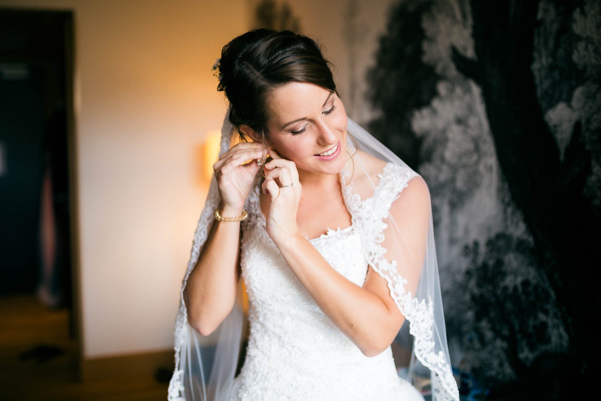 Die Braut beim getting Ready am Morgen der Hochzeit im Hotelzimmer im Taunus, als sie sich Ohrringe anlegt.