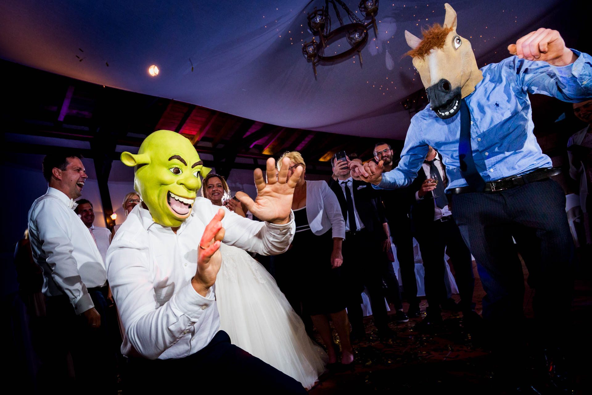 Ausgelassener Tanz auf der Tanzfläche: Dynamische Aufnahmen, die die Energie und Freude der mit Fotobox-Requisiten verkleideten Hochzeitsgesellschaft während des Tanzens einfangen.