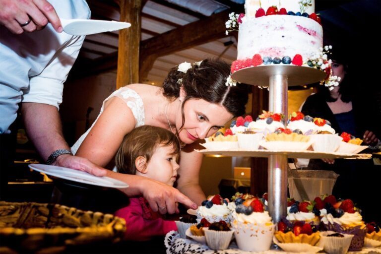 Die Braut bietet einem Kind Hochzeitstorte auf dem Hofgut an.