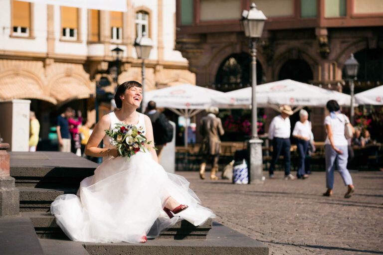 Die Braut sitzt auf der Treppe zum Frankfurter Römer nach ihrer Hochzeit.
