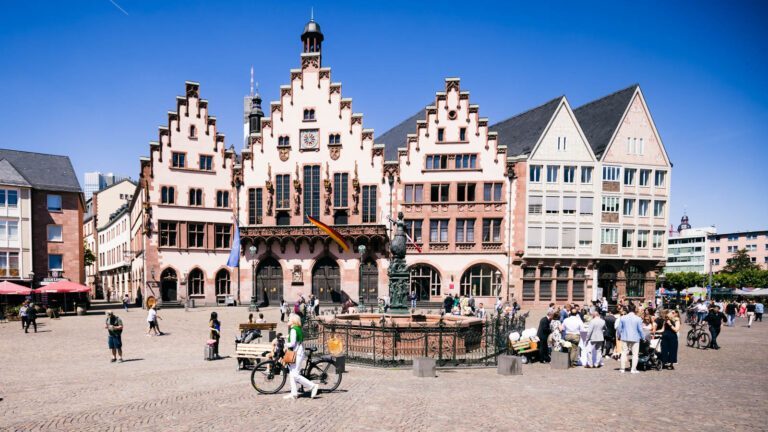 Stadtansicht des berühmten Frankfurter Römers mit Justiziabrunnen und historischen Fachwerkhäusern.