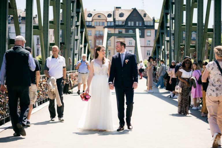 Romantisches Brautpaarshooting nach einer Hochzeit im Römer: Lebendige Fotografien, die das Paar in der urbanen Kulisse des Mainufers einfangen.